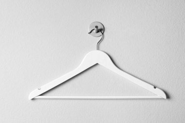 Boş ahşap elbiseler beyaz duvarda asılı.