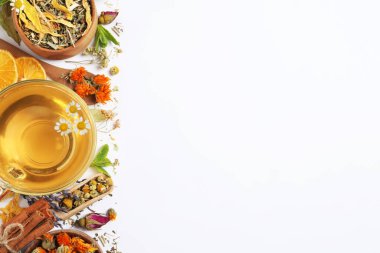 Taze demlenmiş çay ve beyaz arka planda kurutulmuş otlar, üst manzara. Metin için boşluk