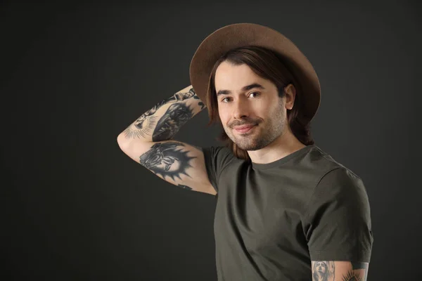 Young man with tattoos on arms against black background