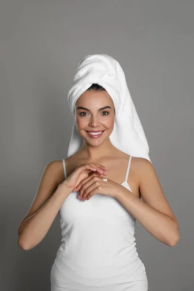 Piękna Młoda Kobieta Ręcznikiem Stosowania Kremu Rękę Szarym Tle — Zdjęcie stockowe