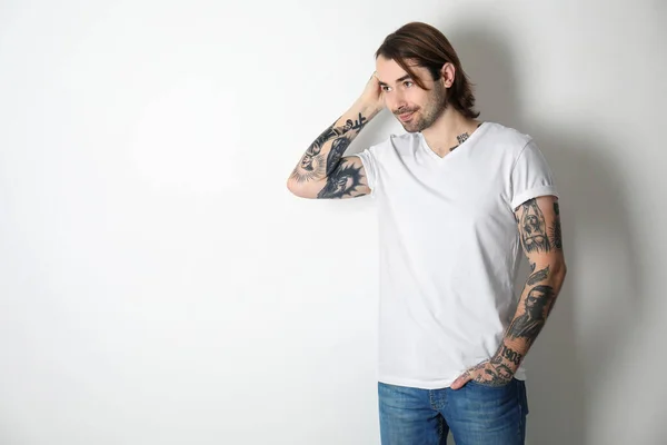 Young man with tattoos on arms against white background