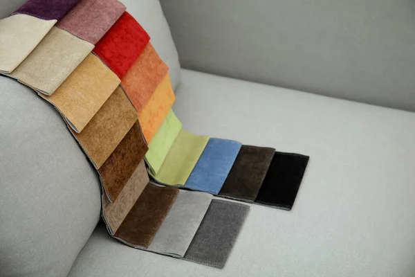 Catalog of colorful fabric samples on grey sofa
