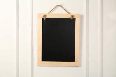 Beyaz duvarda asılı temiz, küçük siyah bir karatahta