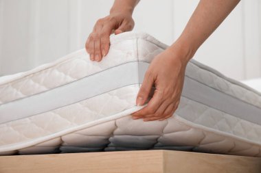 Woman putting soft white mattress on bed indoors, closeup clipart