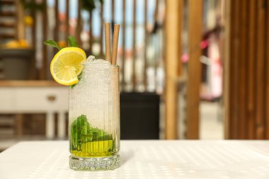 Bir bardak ferahlatıcı narenciye içeceği beyaz masa içinde, mesaj için yer var.