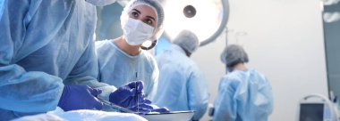 Profesyonel cerrahlardan oluşan bir ekip klinikte ameliyat yapıyor. Mesaj için yer var. Pankart tasarımı