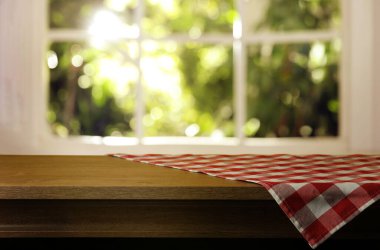 İçerideki ahşap masa üzerinde kırmızı ve beyaz kareli masa örtüsü, tasarım için yer. Bokeh etkisi