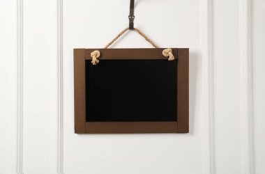 Beyaz duvarda asılı temiz, küçük siyah bir karatahta