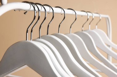 Beyaz elbise askıları metal askılarda bej arka planda, yakın plan