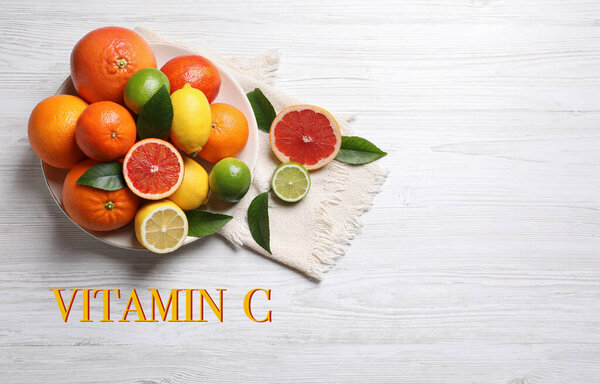 Источник витамина С. Различные цитрусовые на белом деревянном столе, плоский уголок
