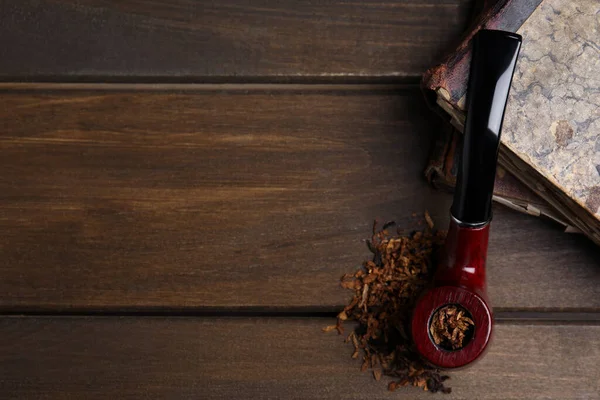 Sigara piposu, kuru tütün ve ahşap masanın üstünde eski kitaplar. Metin için boşluk