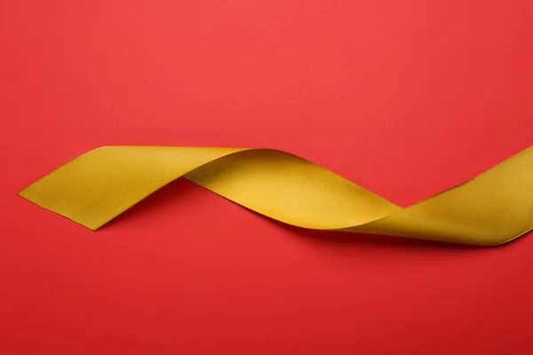 赤い背景の美しい黄金のリボン トップビュー — ストック写真