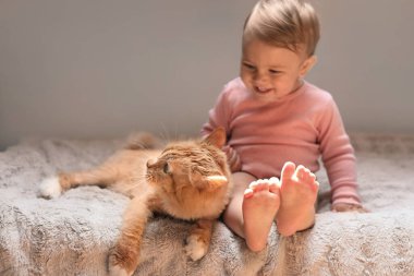 Sevimli bebek ve sevimli kırmızı kedi yatağın içinde