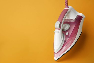 Turuncu arka planda modern bir ütü, metin için boşluk. Ev aletleri