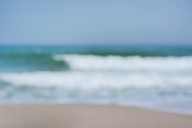 Deniz dalgaları ve kumsalın bulanık görüntüsü. Yaz tatili