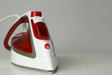 Açık gri arka planda modern bir ütü, metin için boşluk. Ev aletleri