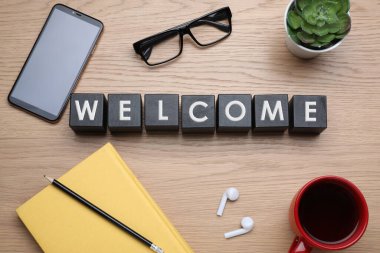 Kelime karşılama, siyah küplerden yapılmış, bir fincan kahve ve ahşap masada akıllı telefon, düz uzanma