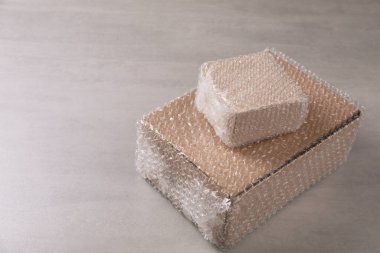 Açık gri masada baloncuklu ambalajla kaplı karton kutular. Metin için boşluk