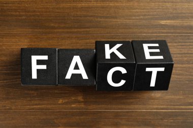 Sahte ve gerçek, tahta masanın üzerinde siyah küplerle yapılmış düz bir şekilde yatıyordu.