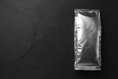 Siyah masada boş folyo paketi, üst görünümde. Metin için boşluk