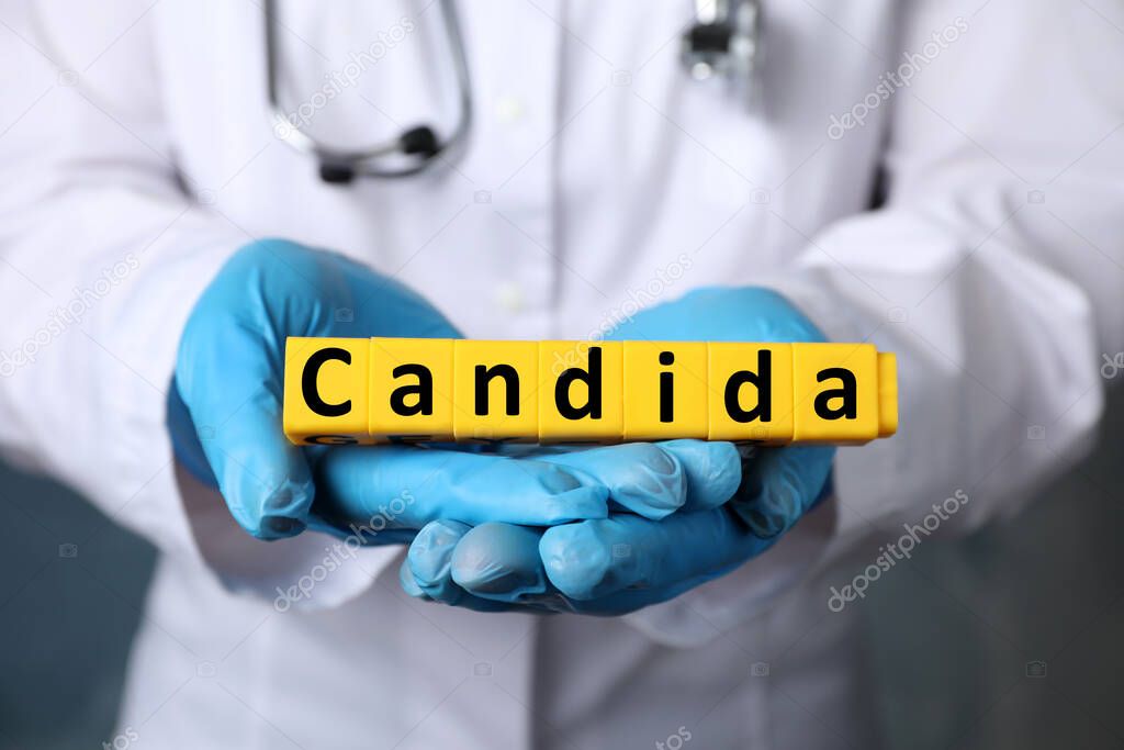 Doctor holding yellow cubes with word Candida, closeup