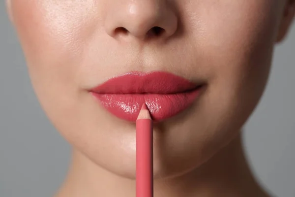 Mujer Joven Aplicando Hermoso Lápiz Labial Rosa Sobre Fondo Gris —  Fotos de Stock