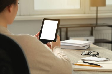 Ahşap masada e-kitap okuyan genç bir kadın, yakın plan.