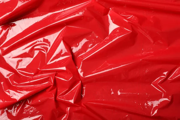 Red plastic stretch wrap as background, top view