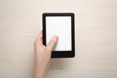 Beyaz ahşap masada e-kitap okuyan bir kadın.