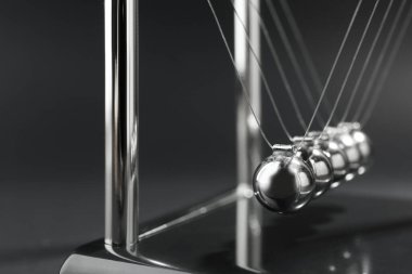 Newton 'un beşiği karanlık arka planda, yakın planda. Enerji korunumunun fizik yasası