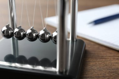 Newton 'un beşiği ahşap masada, yakın plan. Enerji korunumunun fizik yasası