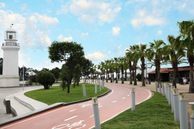 Deniz feneri, palmiyeler ve iki yönlü bisiklet yolu olan bir tatil köyü.