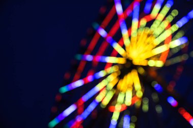 Karanlık gökyüzüne karşı parlayan güzel dönme dolabın bulanık görüntüsü.