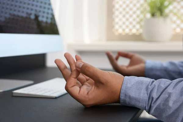 Businessman meditating at workplace, closeup. Zen concept