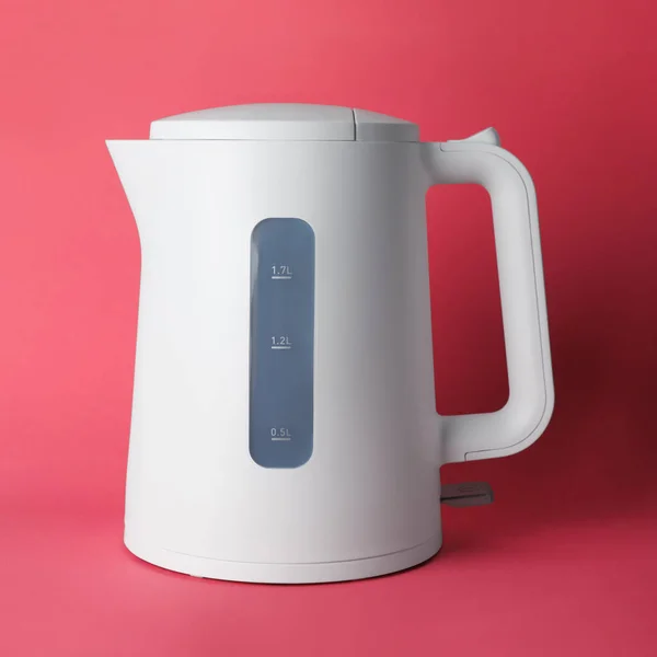 New modern electric kettle on red background