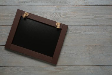 Gri ahşap masadaki temiz, küçük siyah karatahta, üst manzara. Metin için boşluk