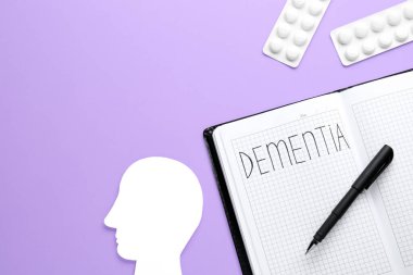 Dementia 'lı defter, haplar ve menekşe arka planda insan kafası kesimi, düz yatış. Metin için boşluk