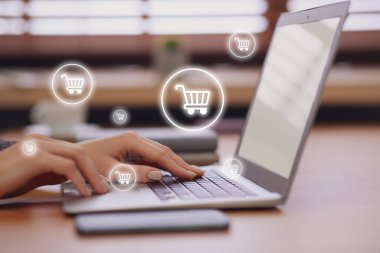 Teslimat konsepti. Modern dizüstü bilgisayarını kapalı mekanlarda alışveriş yapmak için kullanan bir kadın. Pazar arabası çizimleri