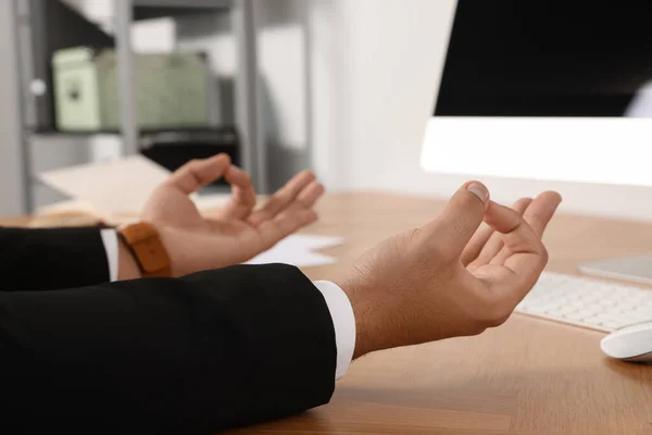 Businessman meditating at workplace, closeup. Zen concept