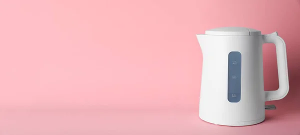 New modern electric kettle on pink background, space for text