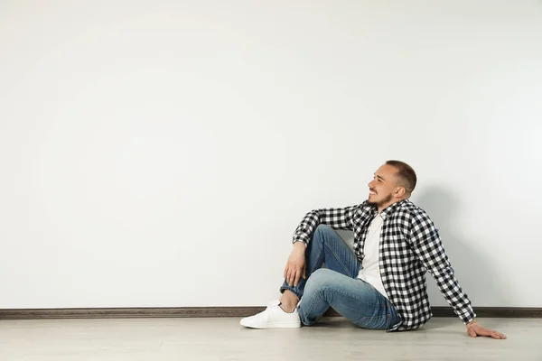 Beyaz Duvarın Yanında Yerde Oturan Yakışıklı Genç Adam Mesaj Için — Stok fotoğraf