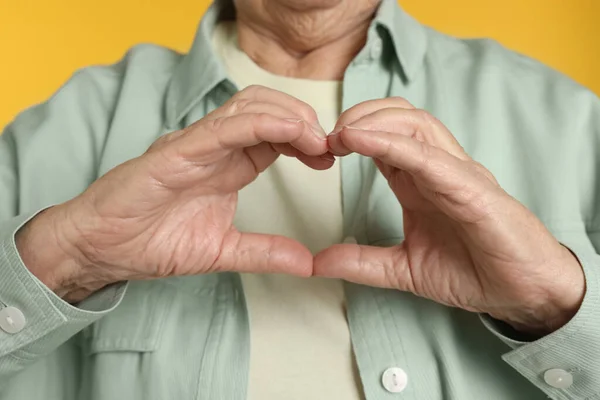 Elderly Woman Making Heart Her Hands Yellow Background Closeup — Stock Photo, Image
