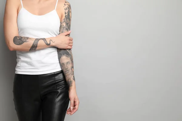 灰色の背景に腕の入れ墨を持つ美しい女性 クローズアップ テキストのスペース — ストック写真
