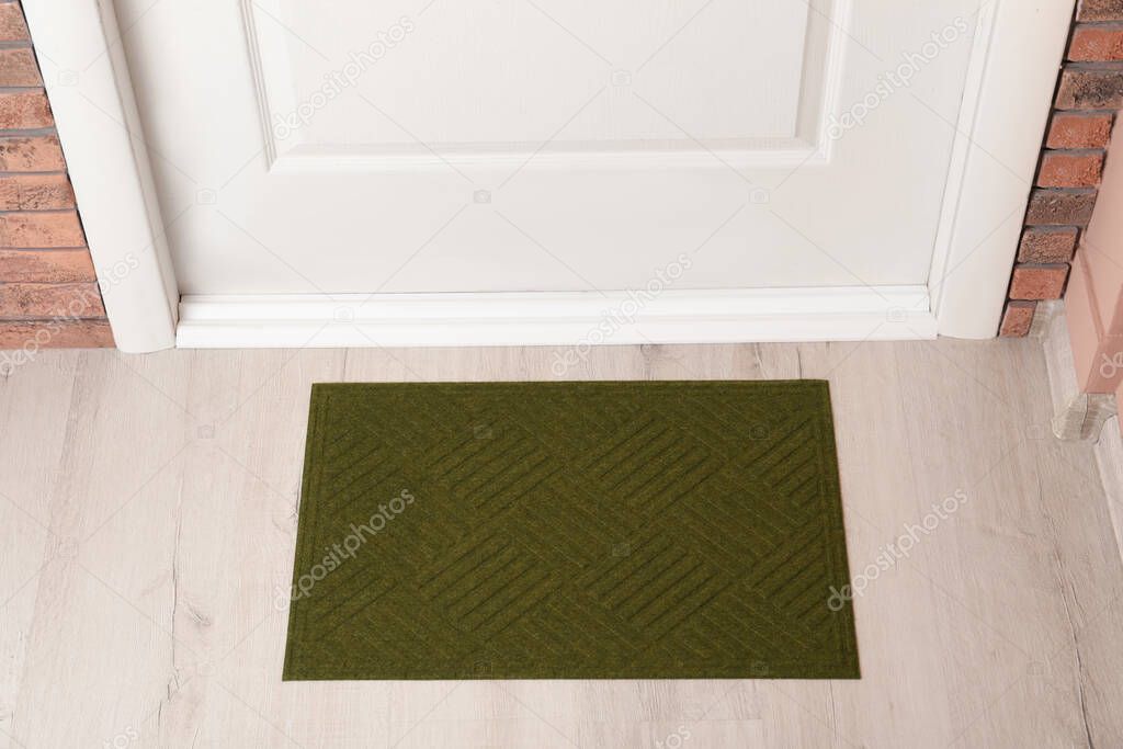 Dark olive door mat on wooden floor in hall, above view
