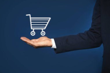 Mavi arka planda alışveriş arabasının sanal görüntüsünü gösteren bir adam.