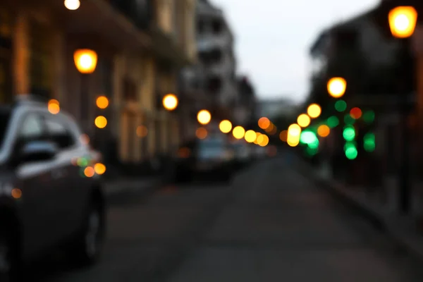 Blurred view of city street with parked cars in evening