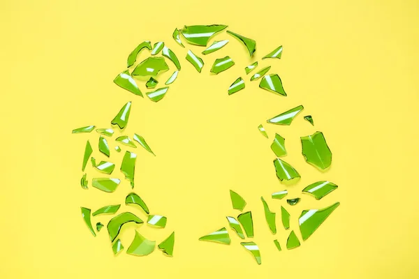 黄色の背景にガラス片で作られたリサイクルシンボル フラットレイ — ストック写真