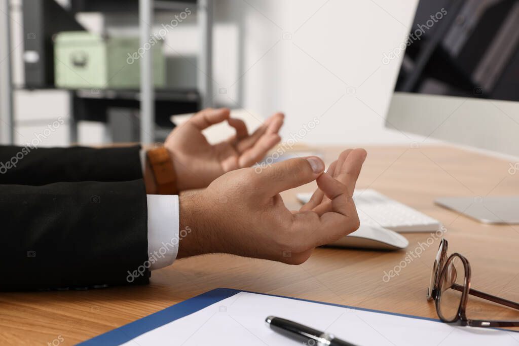 Businessman meditating at workplace, closeup. Zen concept