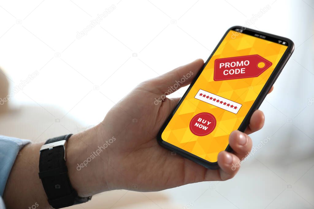Man holding smartphone with activated promo code in online shopping app indoors, closeup