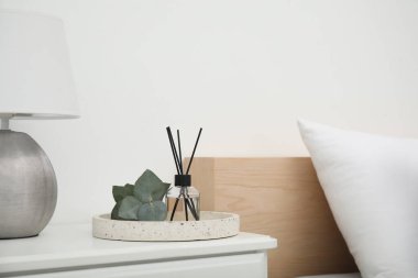 Yatak odasındaki komodinin üzerinde lamba ve okaliptüs ile Reed dağıtıcı